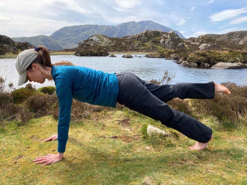 Pilates teacher Carla Hüsselmann demonstrates the Pilates exercise, Leg Pull Front, on the top of Haystacks Mountain in the Lake District
